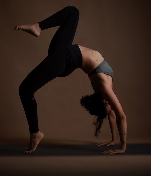 Woman practicing yoga on a mat in a dark studio.